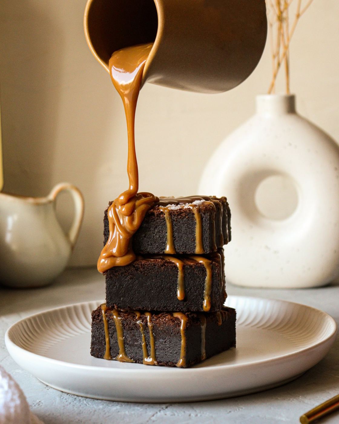 Caramel poured over a stack of salted brownies