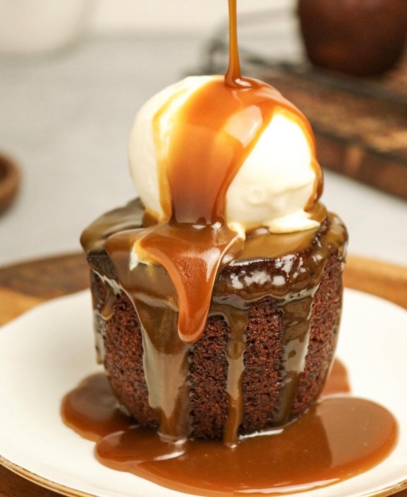 Sticky toffee pudding with ice cream and a pour of toffee sauce